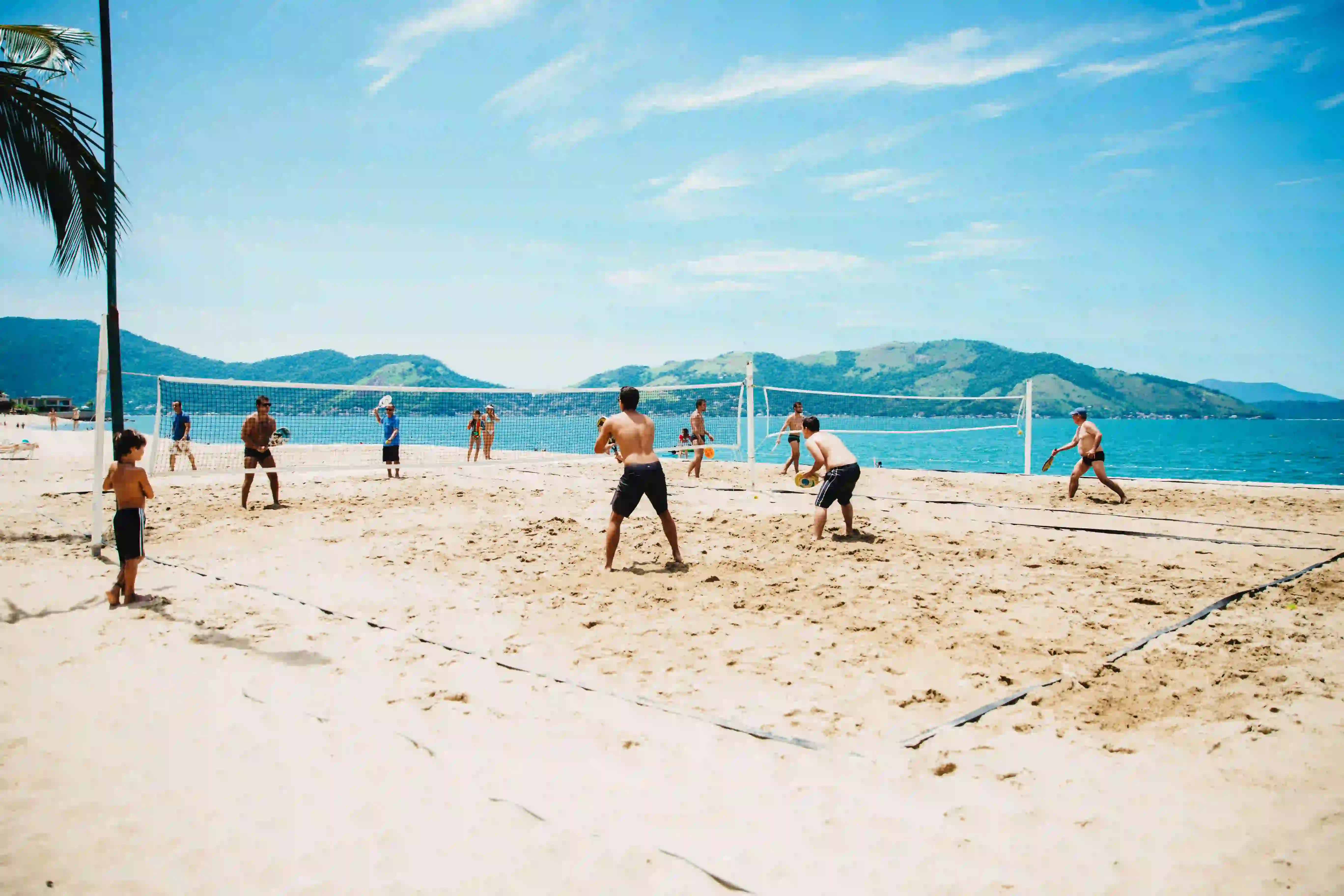 Jogadores de beach tennis na praia ao pôr do sol
